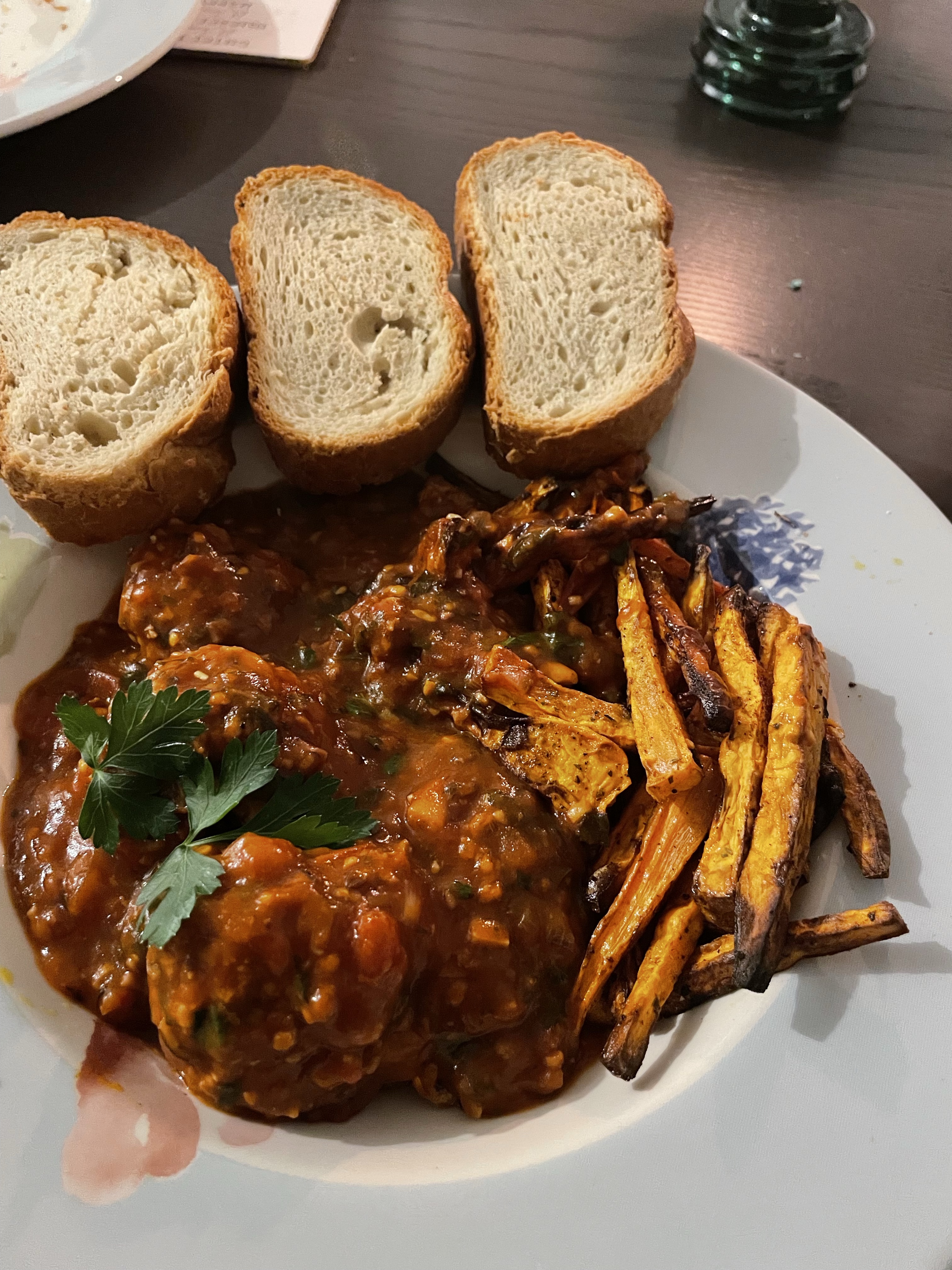 Albóndigas auf einem Teller; serviert mit Brot und Süßkartoffelpommes.
